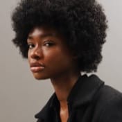 photo of a girl with dark skin, dark hair and dark shirt.